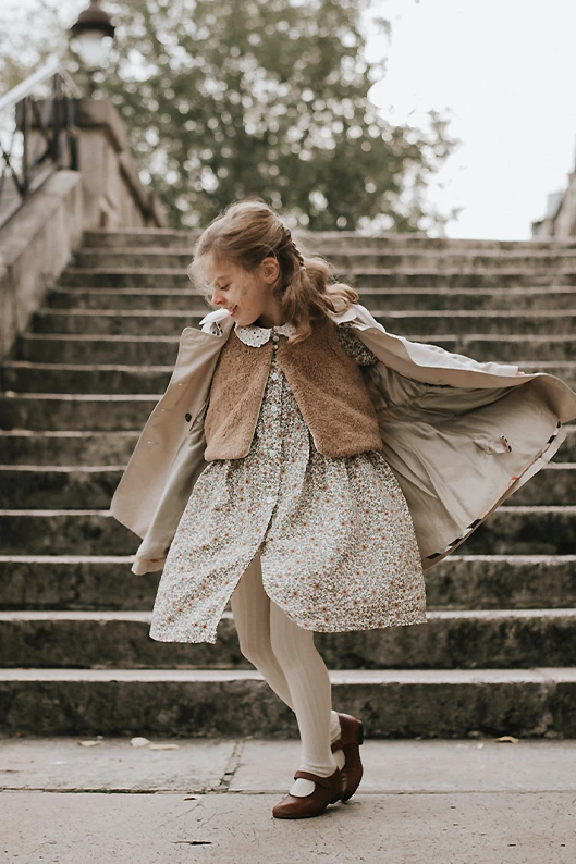 Portrait lifestyle d’un enfant qui descend des marches en sautillant dans une rue parisienne.