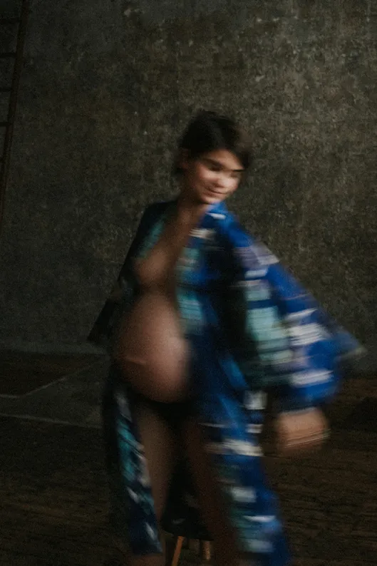 Portrait artistique d’une femme enceinte en kimono bleu, photographiée au studio dans un mouvement dansé flou.